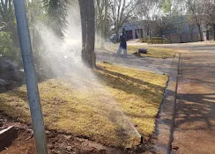Sprinklers watering a street-front lawn after an irrigation job